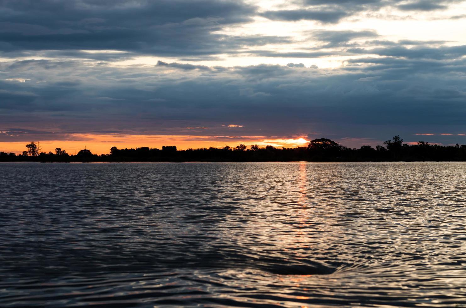 il sole arancione si illumina con le onde dell'acqua. foto