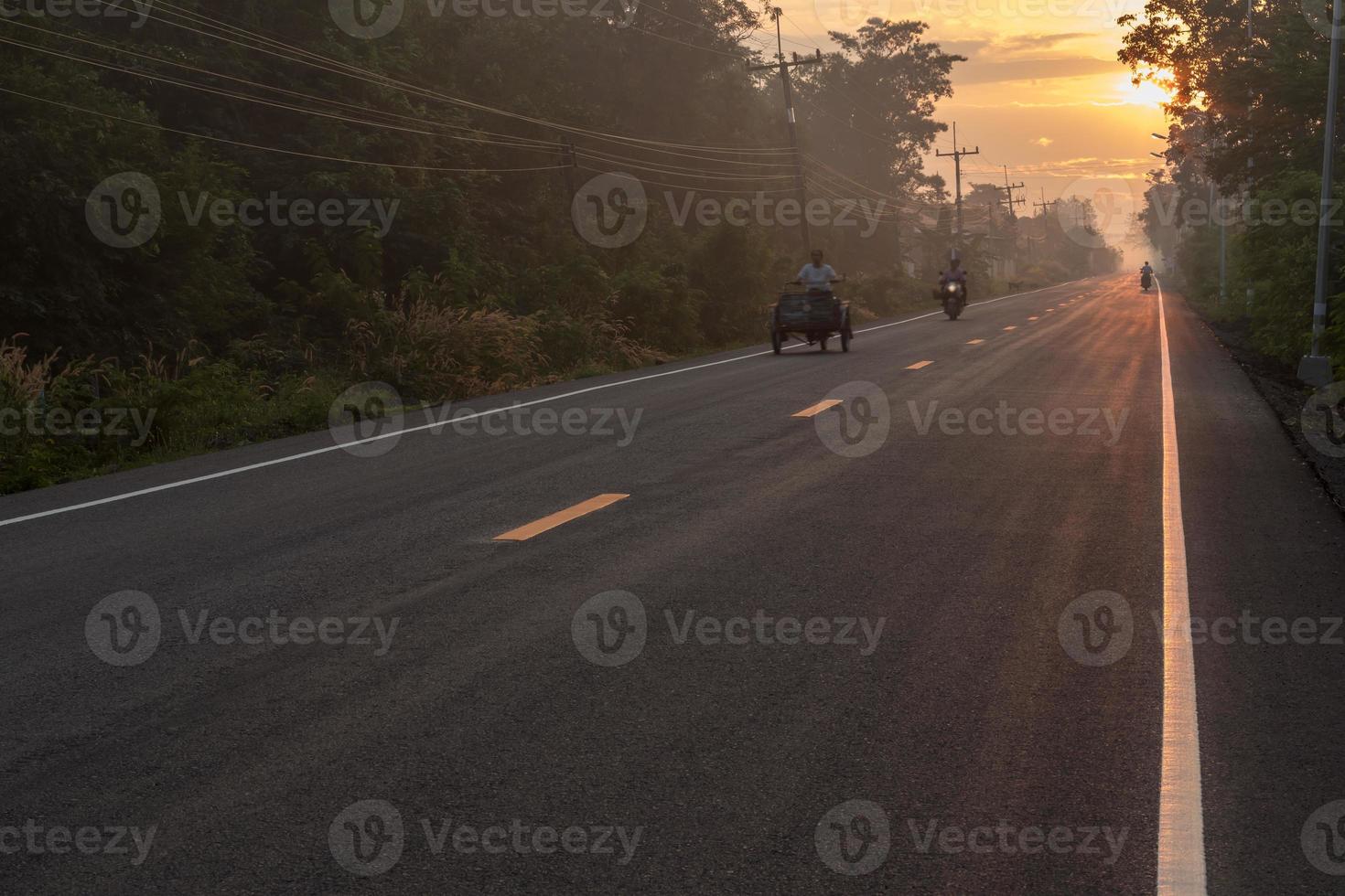 strada asfaltata con il sole che sorge in campagna. foto