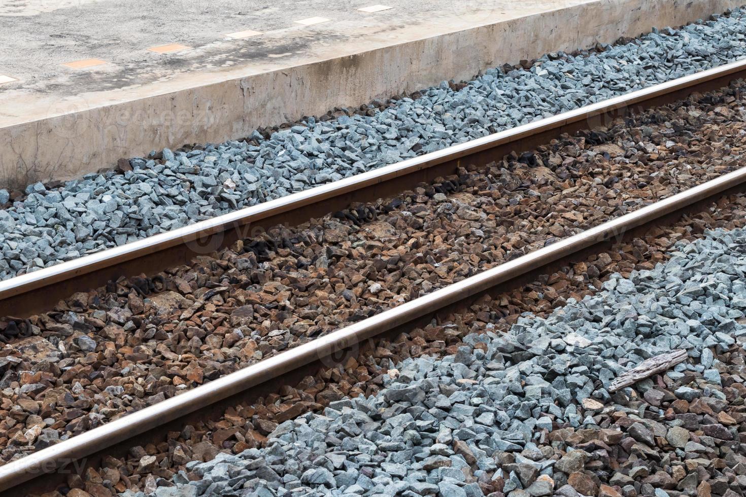 binari ferroviari con rocce vicino al cemento. foto