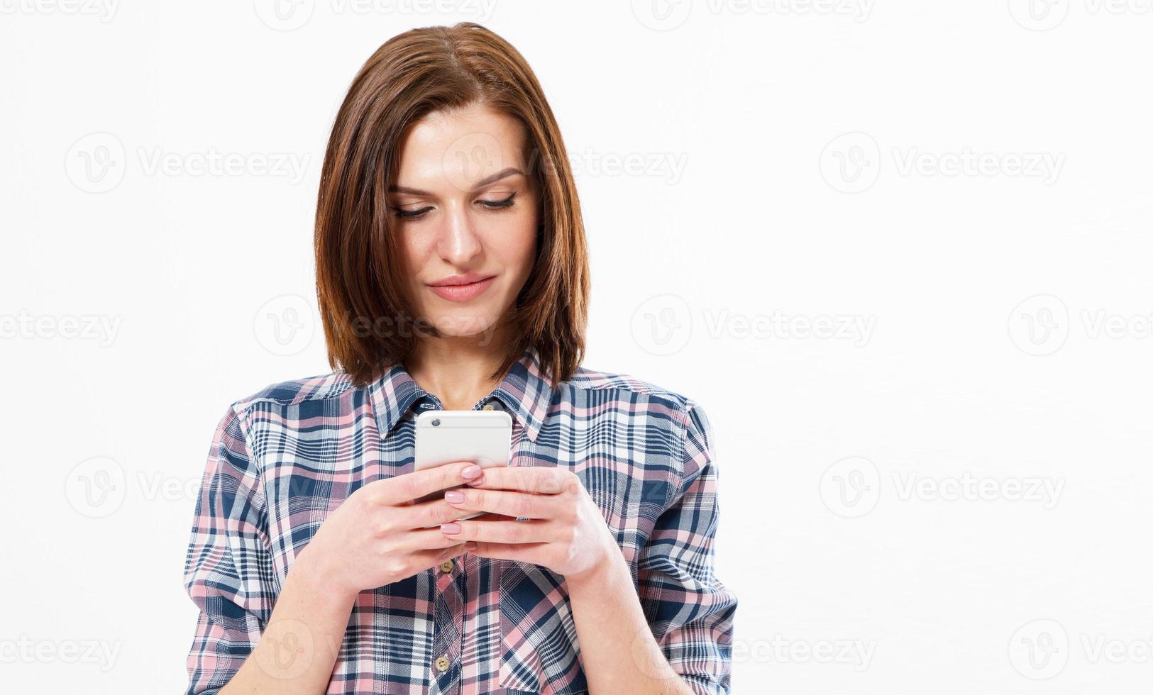 ragazza felice che scrive sms su sfondo bianco copia spazio, immagine di una donna bruna sorridente che utilizza lo smartphone. foto