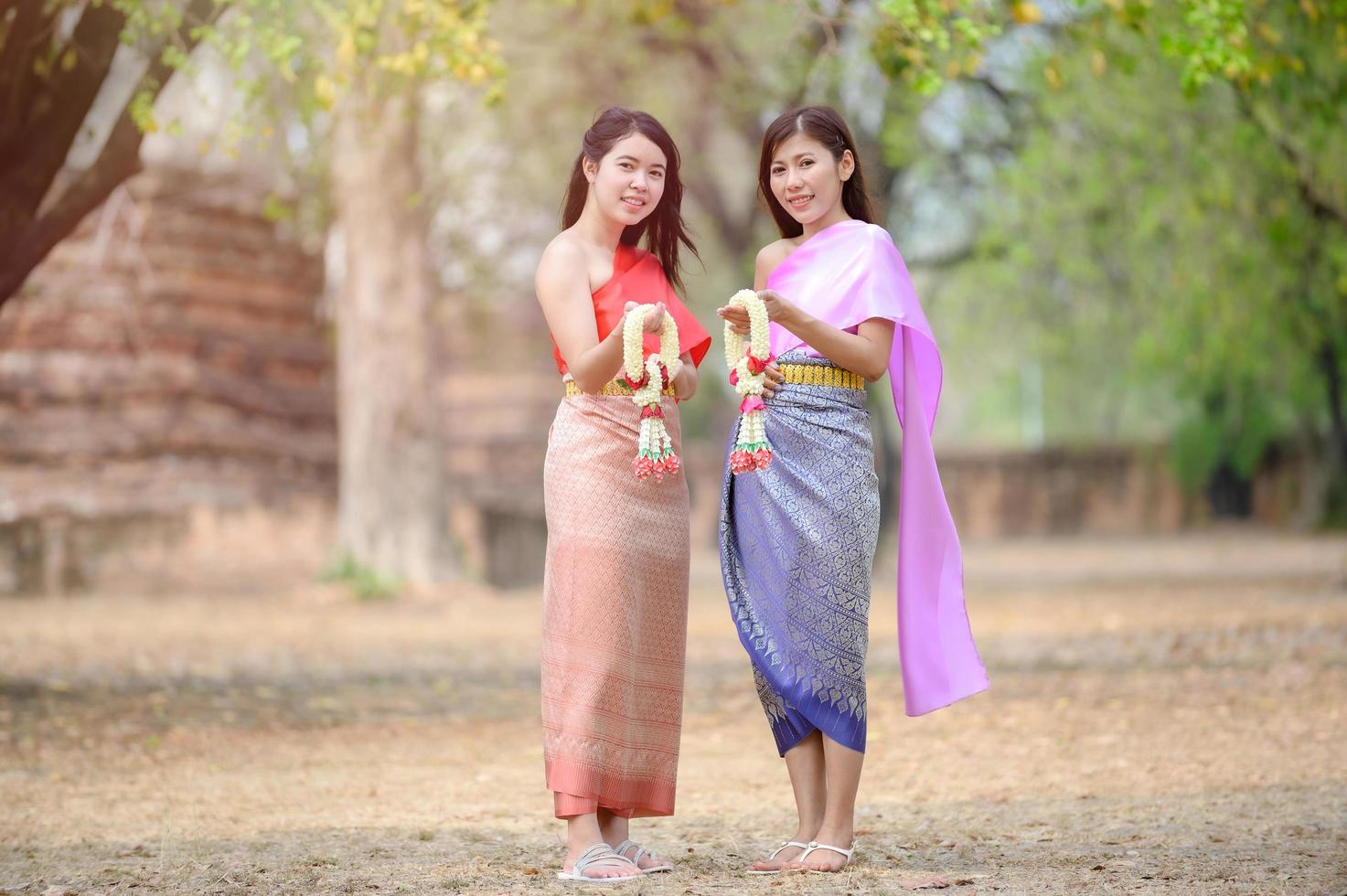 donne tailandesi attraenti nel tradizionale abito tailandese tengono ghirlande di fiori freschi per entrare in un tempio basato sulla tradizione del festival di songkran in tailandia foto