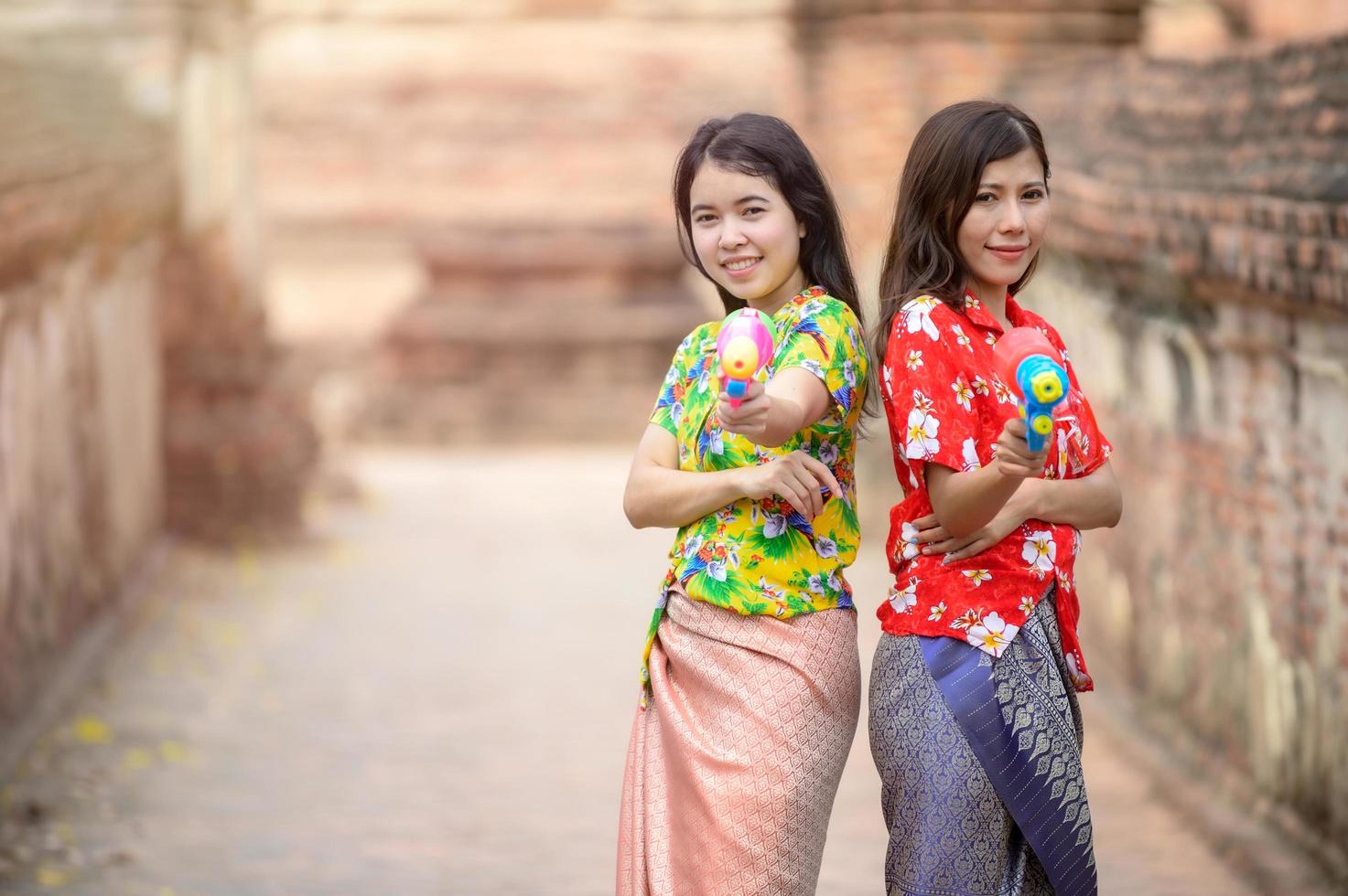 belle donne asiatiche tengono pistole ad acqua di plastica in un antico tempio durante il Songkran, il festival dell'acqua più bello e divertente della Thailandia foto