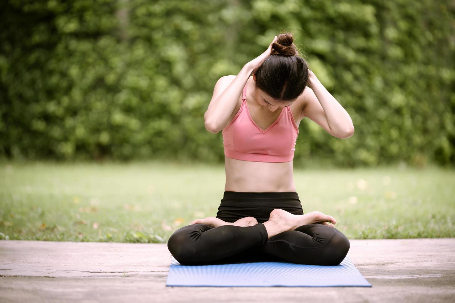 la meditazione e lo stretching delle donne asiatiche rilassano i muscoli facendo yoga in giardino foto