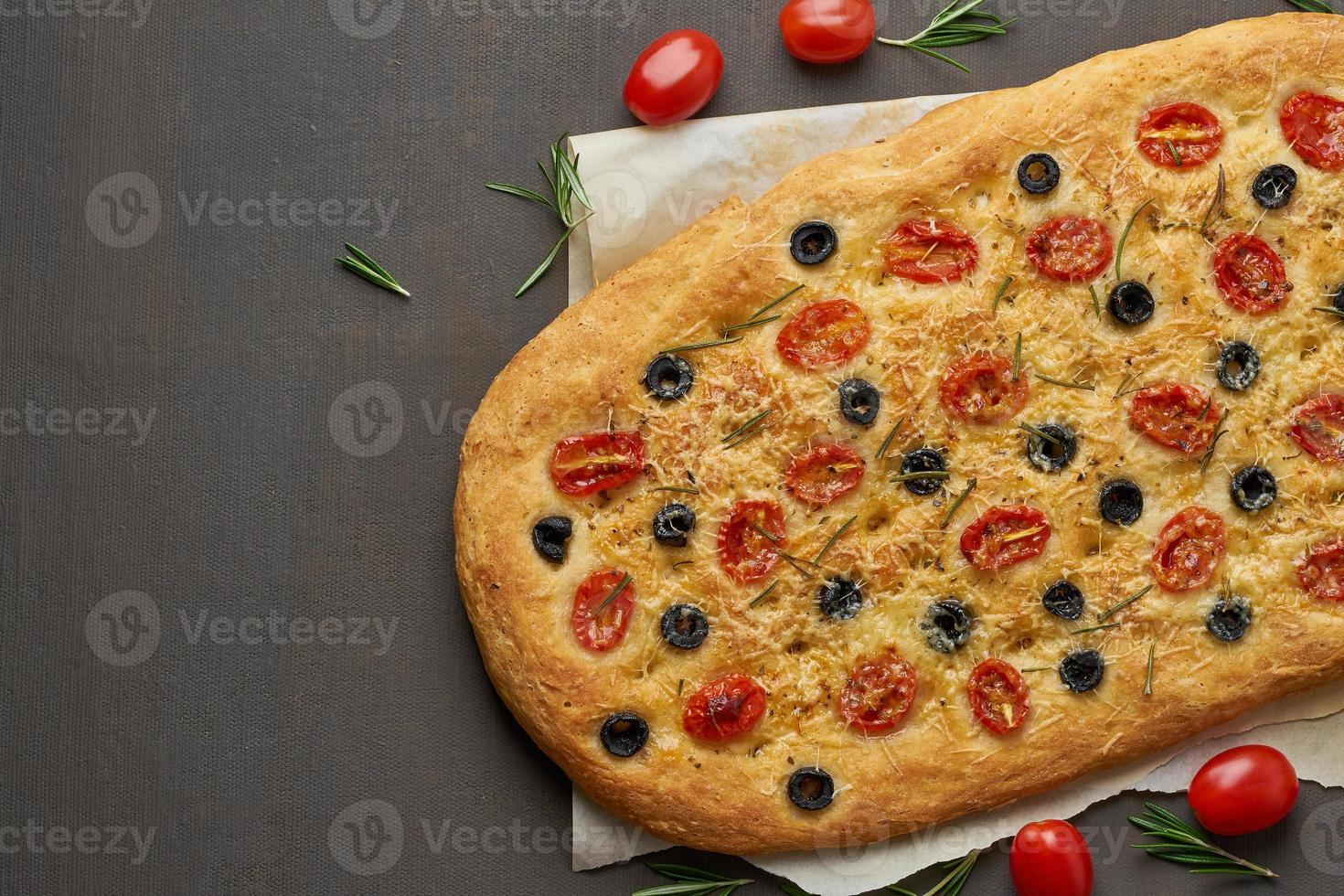 focaccia, pizza, focaccia italiana con pomodori, olive e rosmarino su tavola marrone, copia spazio foto