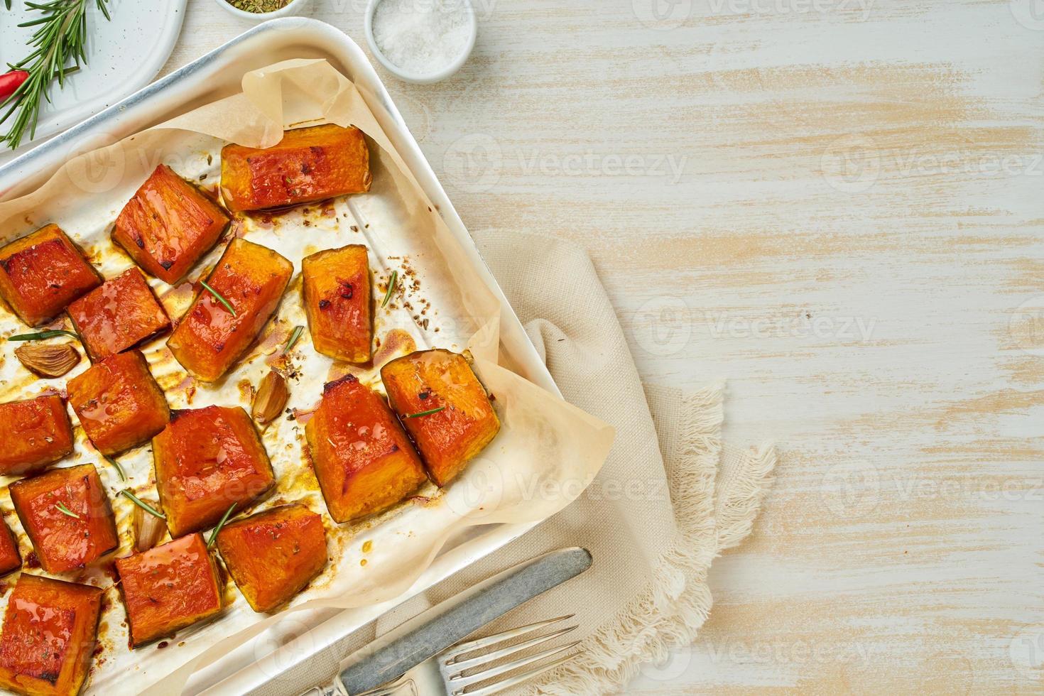 vassoio con pezzi arrostiti di zucca dolce con miele e condimenti, vista dall'alto foto