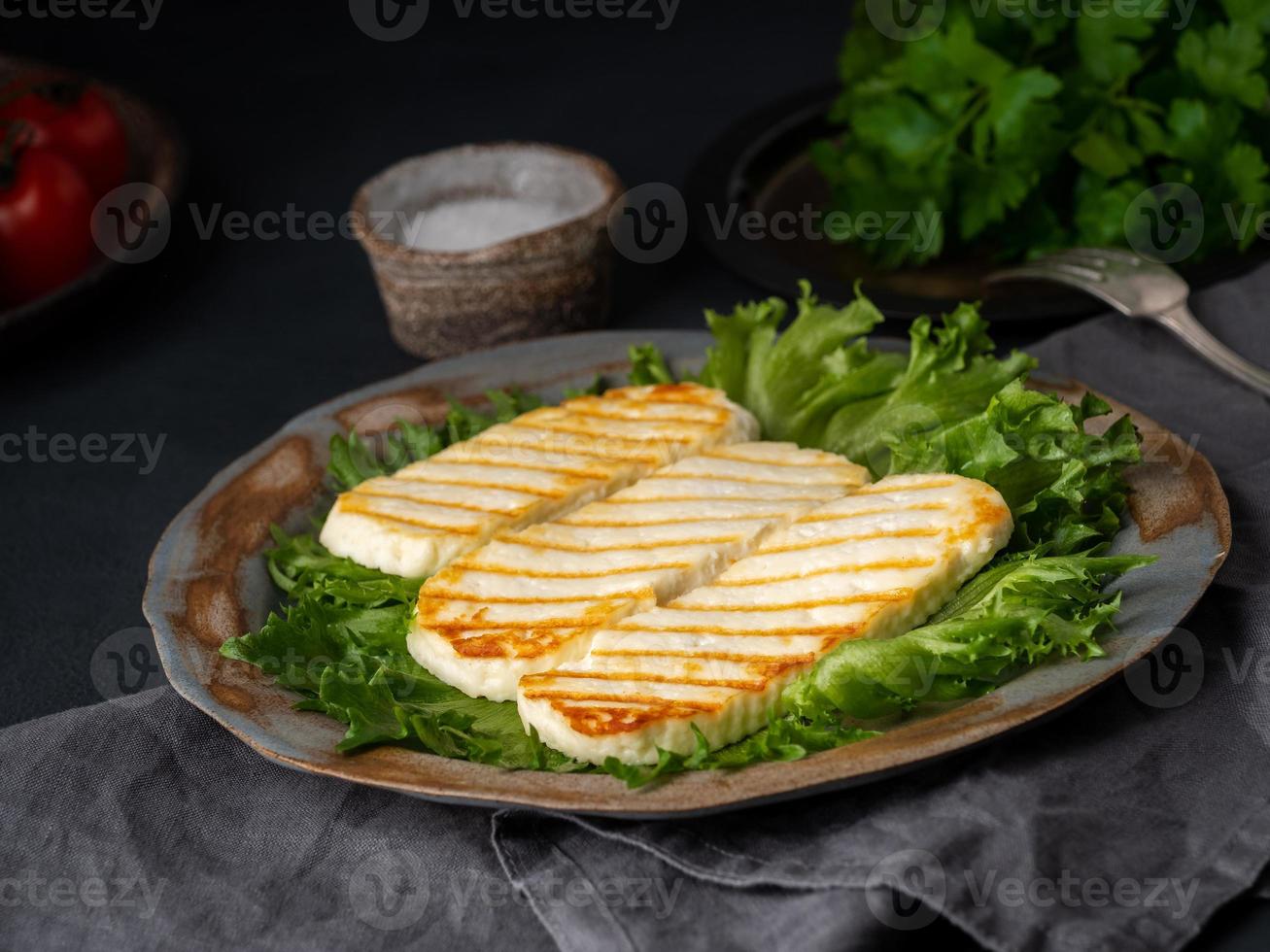 halloumi alla griglia, formaggio fritto con insalata di lattuga. dieta equilibrata su sfondo scuro, vista laterale foto