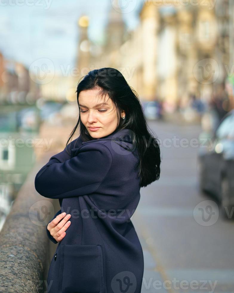 ritratto f bella bruna intelligente che cammina per la strada di san pietroburgo nel centro della città. affascinante donna premurosa con lunghi capelli scuri vaga da sola, immersa nei pensieri foto