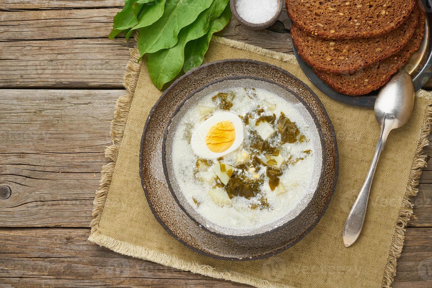 zuppa di acetosa con panna e uova, fondo in legno, vista dall'alto con spazio per la copia foto