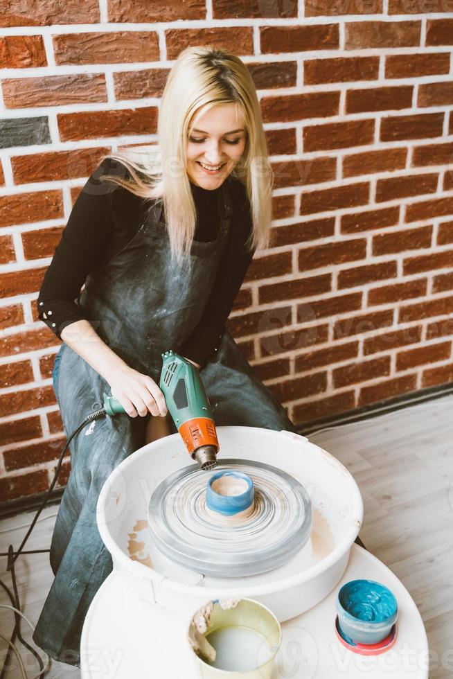 donna che fa ceramiche su ruota, sbozzi di argilla asciugati con il phon. concetto per donna in freelance, affari. prodotto artigianale. guadagnare soldi extra, fare affari, trasformare gli hobby in denaro e la passione in lavoro foto