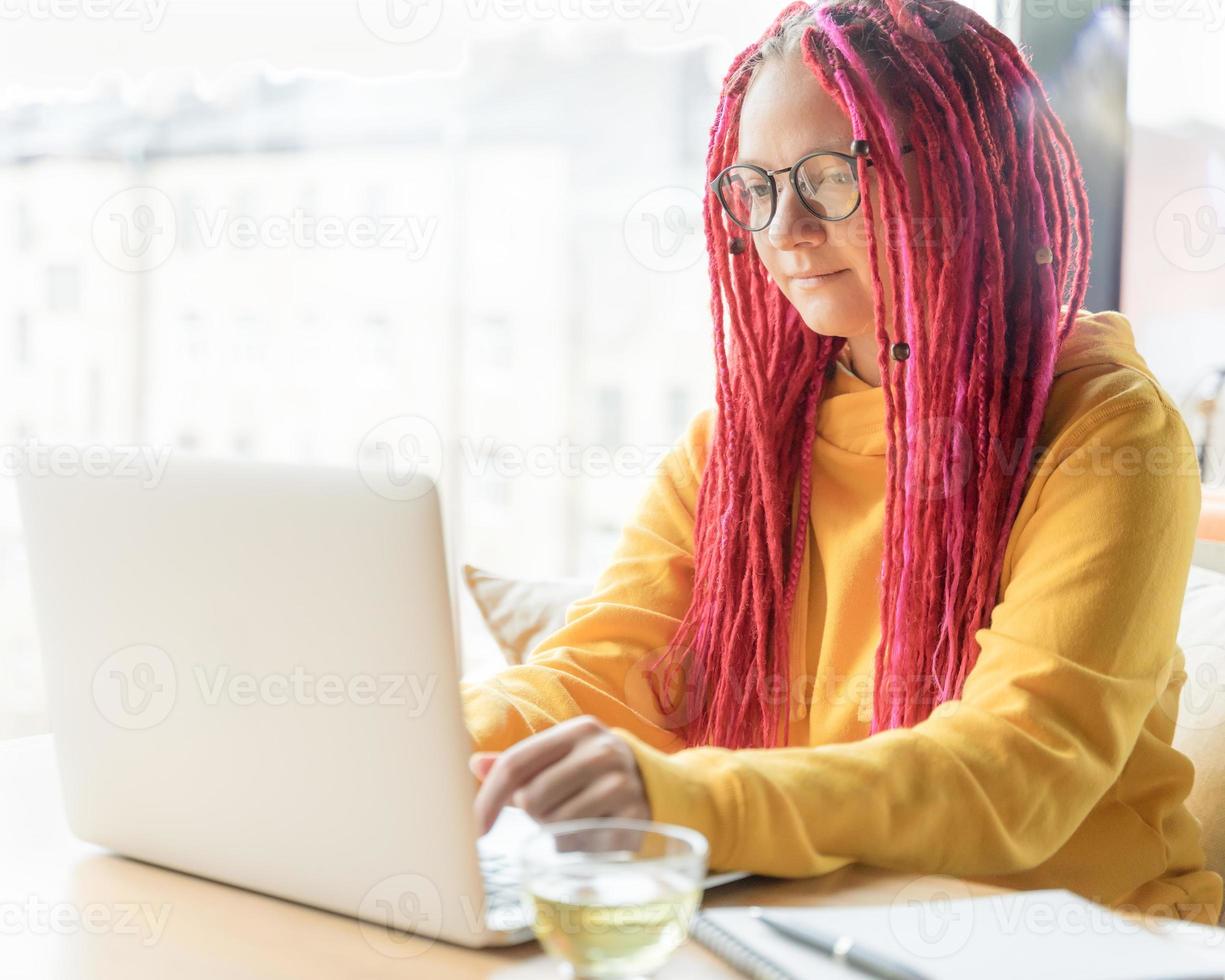 concetto di nomade digitale. ragazza freelance che lavora a distanza sul laptop in un bar, coworking. foto