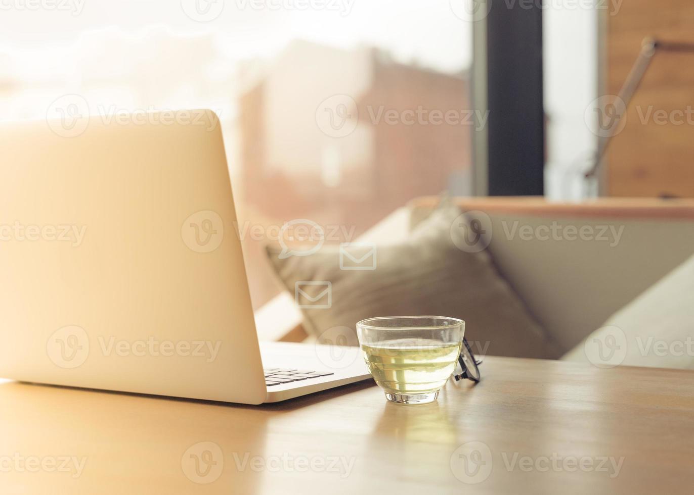 scrivania freelance con laptop aperto, tazza di tè verde e bicchieri sul tavolo. bar o spazio di coworking. concetto di nomadi digitali, ufficio a casa, blog foto