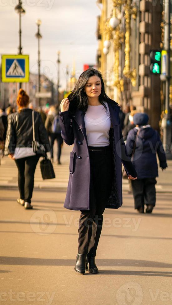 bella ragazza bruna seria intelligente che cammina per strada di st. pietroburgo nel centro della città. affascinante donna premurosa con lunghi capelli scuri vaga da sola foto