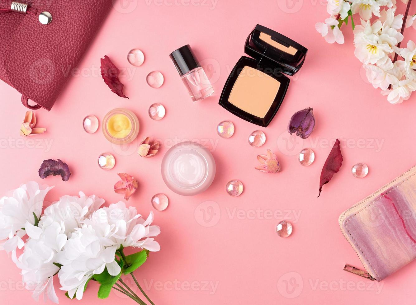 accessori donna piatti con cosmetici, crema viso, borsa, fiori su tavolo rosa brillante. foto