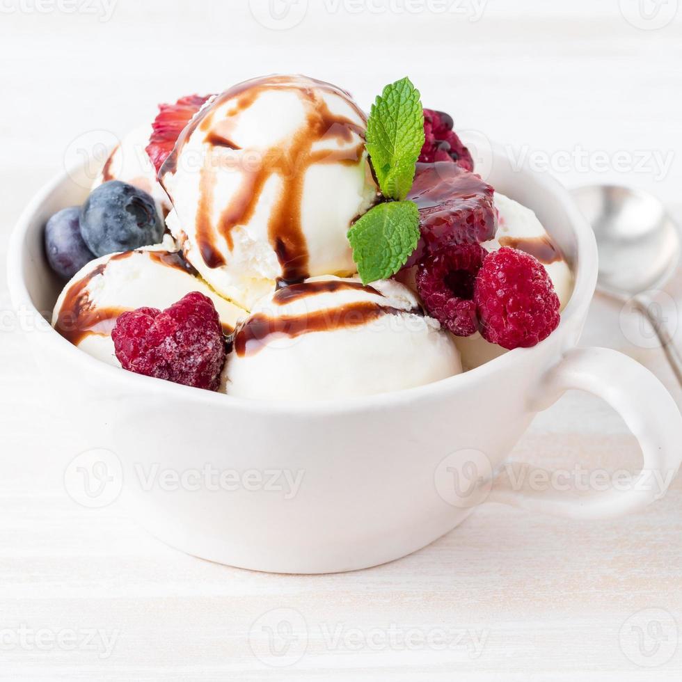 palline di gelato alla vaniglia in tazza con lampone e mirtilli, cioccolato foto