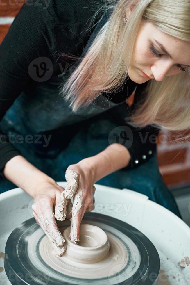 bella donna che fa la ceramica sulla ruota, primo piano. concetto per donna in freelance, affari, hobby. guadagnare soldi extra, fare soldi, trasformare gli hobby in denaro e la passione in un lavoro foto