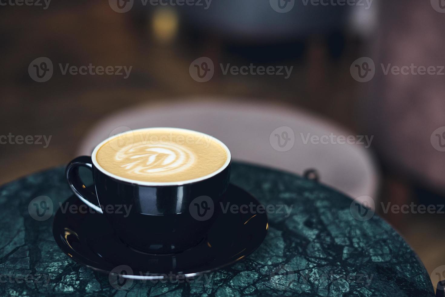 una tazza di cappuccino con schiuma su un tavolo di marmo vicino alla finestra in un piccolo e accogliente caffè. bere con latte vegetale, farina d'avena, cocco foto