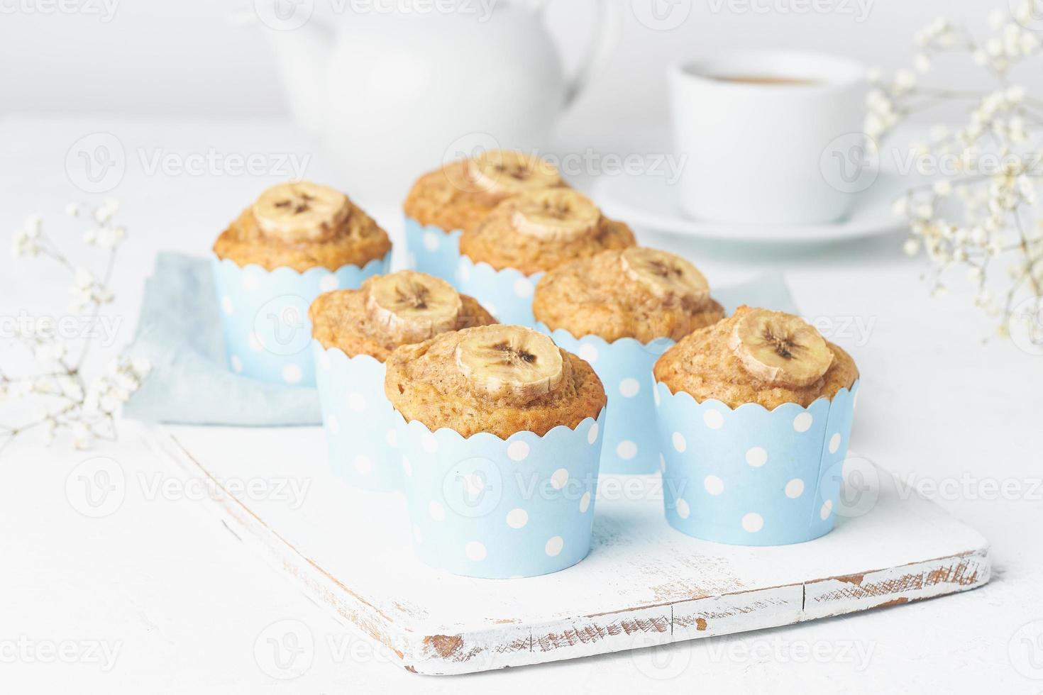 muffin alla banana, cupcakes in pirottini di carta blu, tavolo in cemento bianco foto