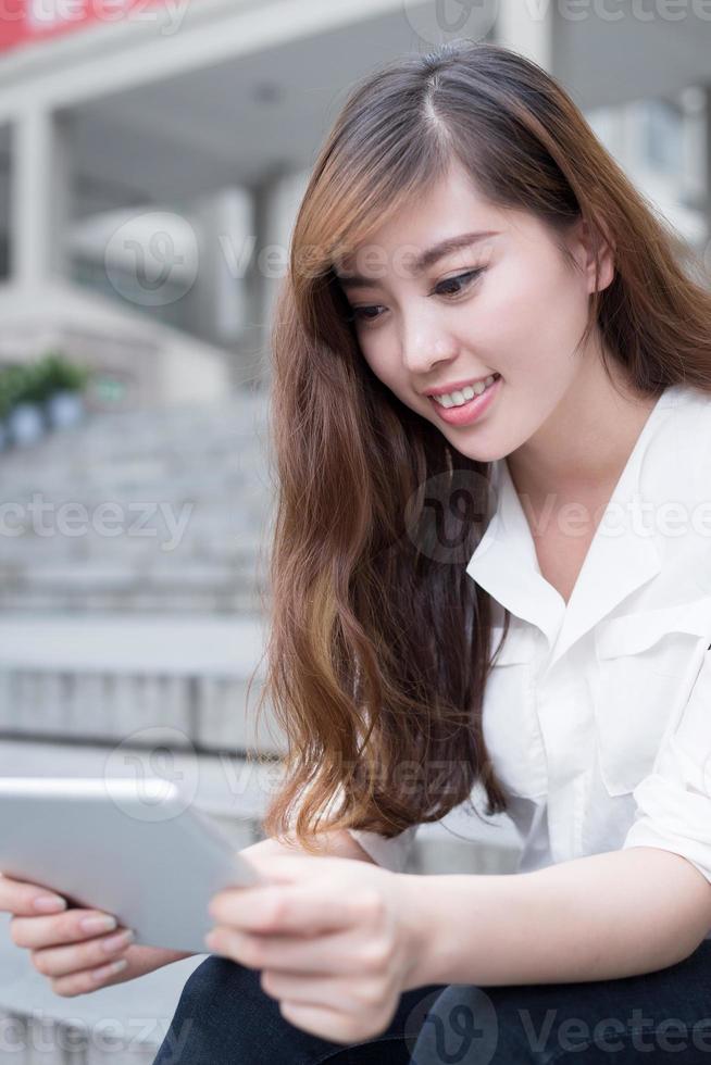 studentessa asiatica che utilizza compressa nel campus foto