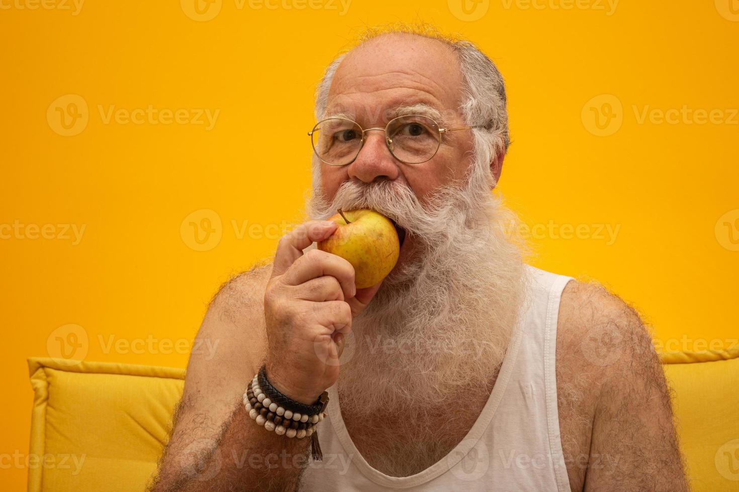 ritratto di un uomo barbuto che sta per mangiare una mela. anziano che mangia una mela. foto