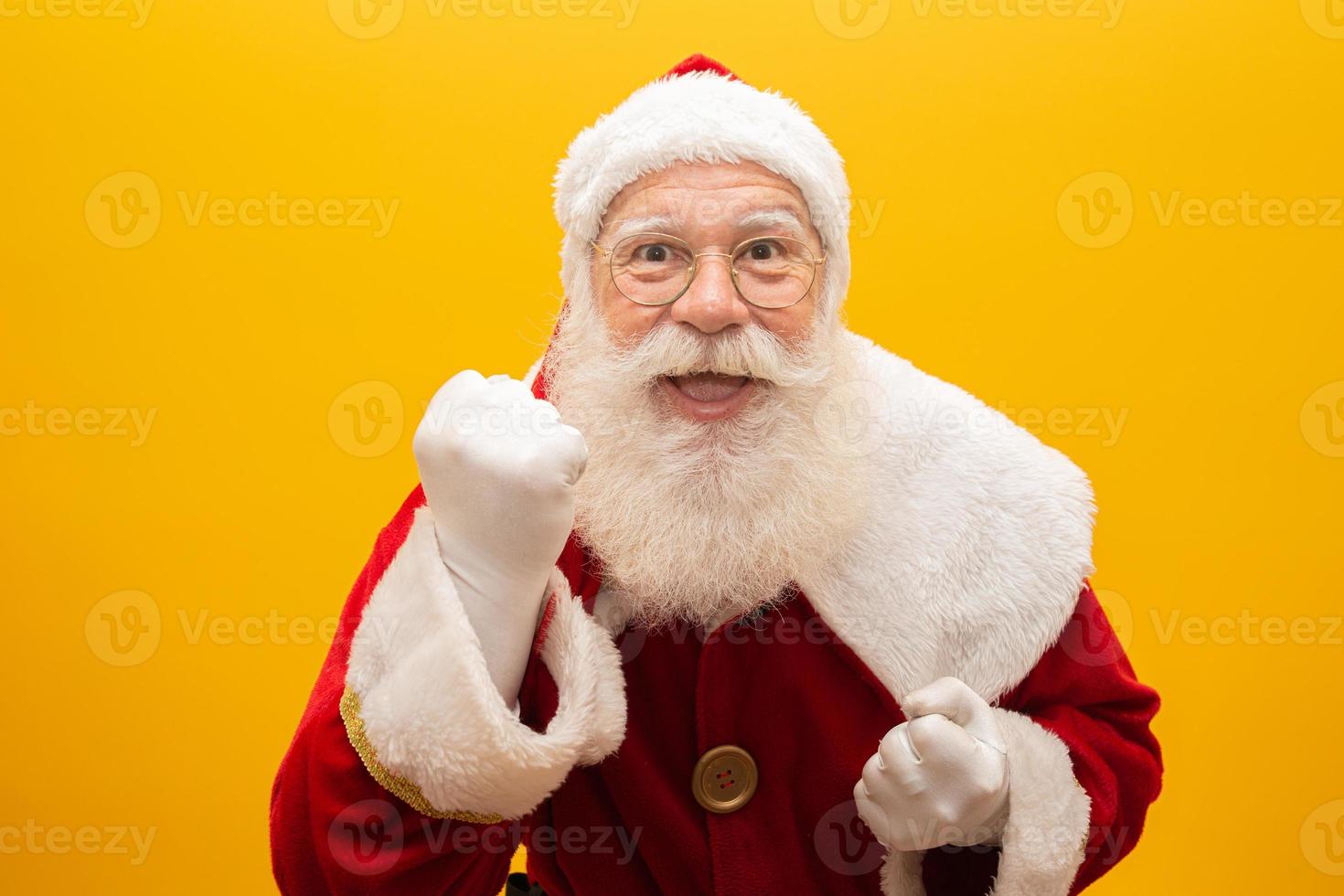 holly jolly natale e noel, fiducia, magia, concetto di trionfo. fresco e divertente nonno giocoso con la bocca spalancata, smorfia comica, scherzando isolato su sfondo giallo, mostra il gesto di vittoria foto