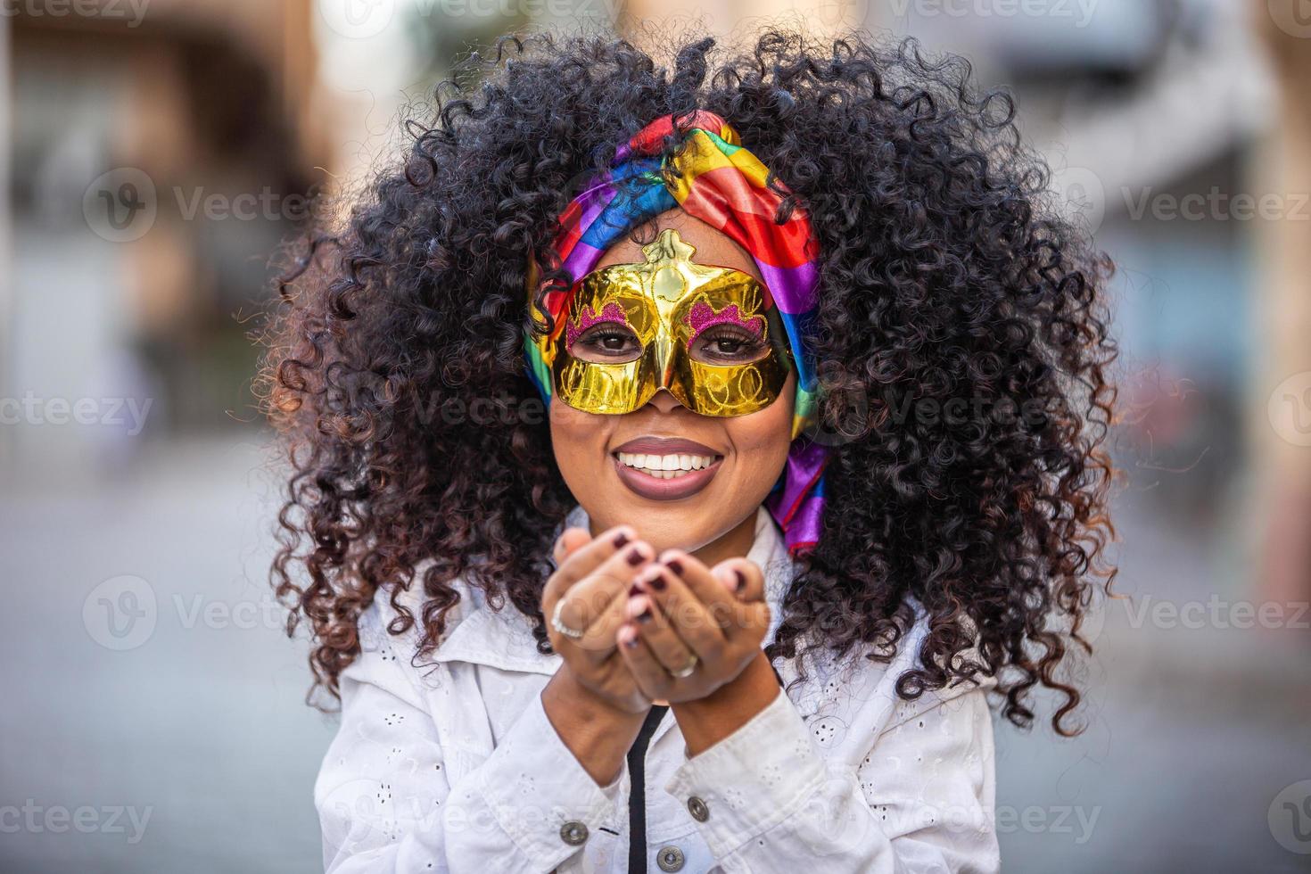 festa di carnevale. donna brasiliana capelli ricci in costume che soffia coriandoli foto