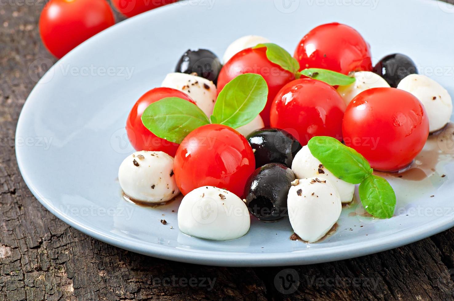 insalata fresca con pomodorini, basilico, mozzarella e olive nere. foto