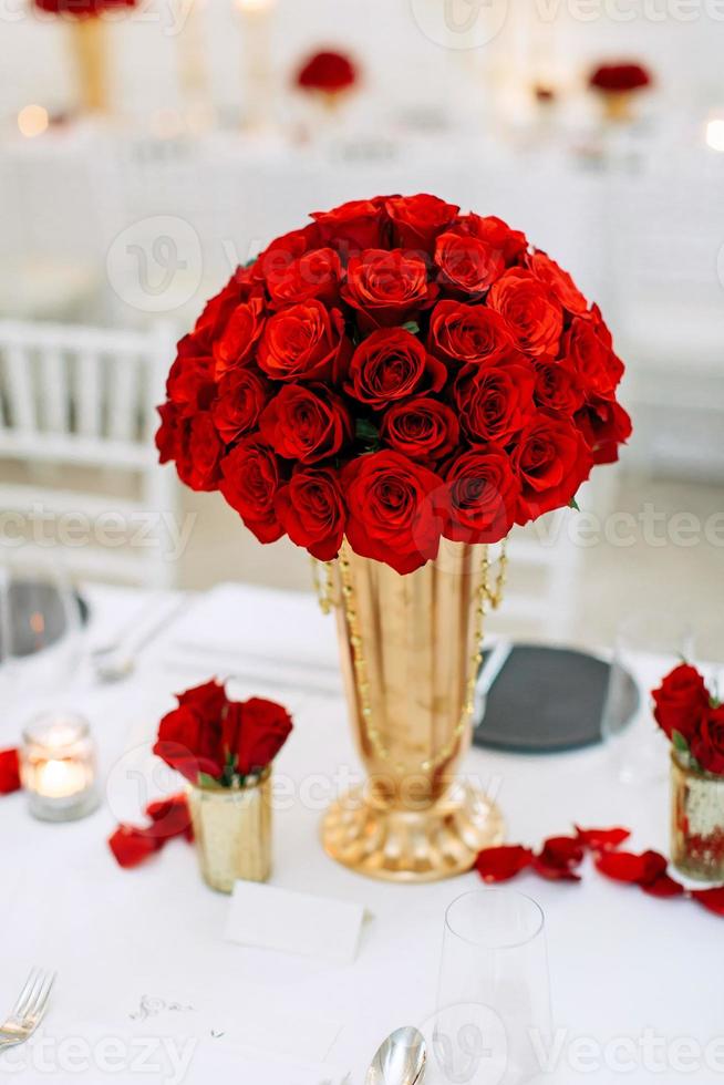 rose rosse in un vaso d'oro in una decorazione da tavola a tema bianco foto
