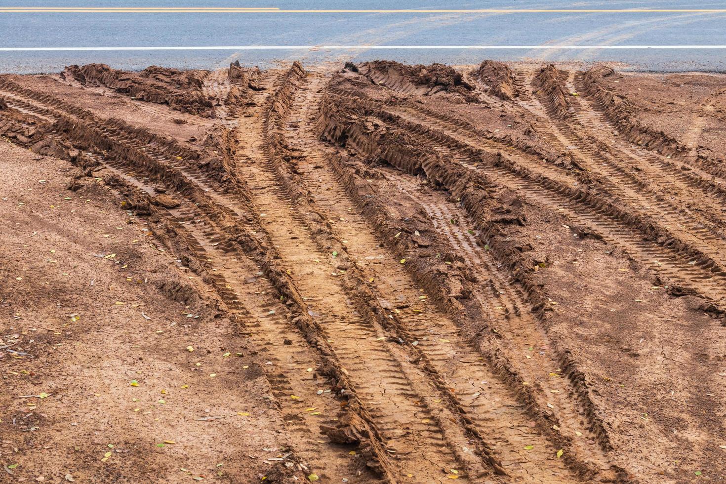 superficie fangosa, terreno sterrato con tracce di ruote su strade asfaltate. foto