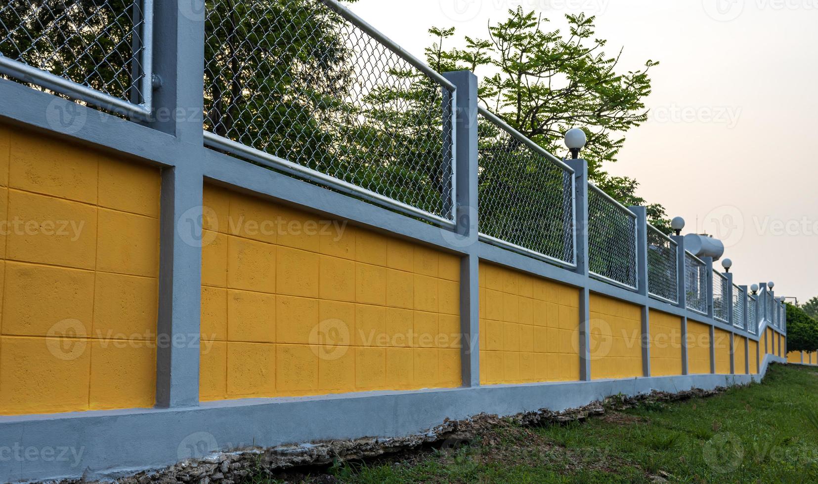 recinzione di muro di cemento giallo con grata in acciaio nel giardino forestale. foto