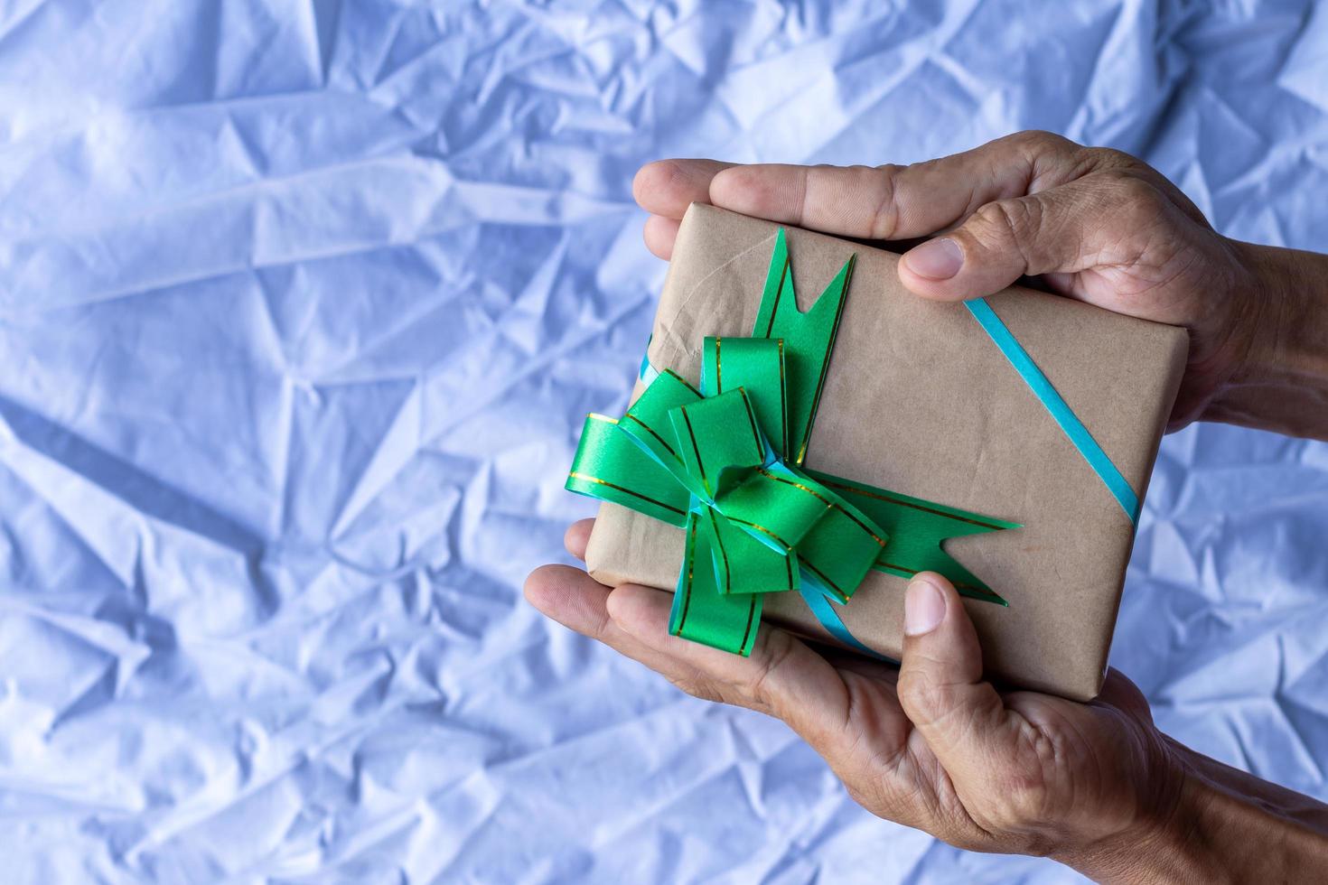 mano che tiene scatola regalo e tela con papillon come sfondo. foto