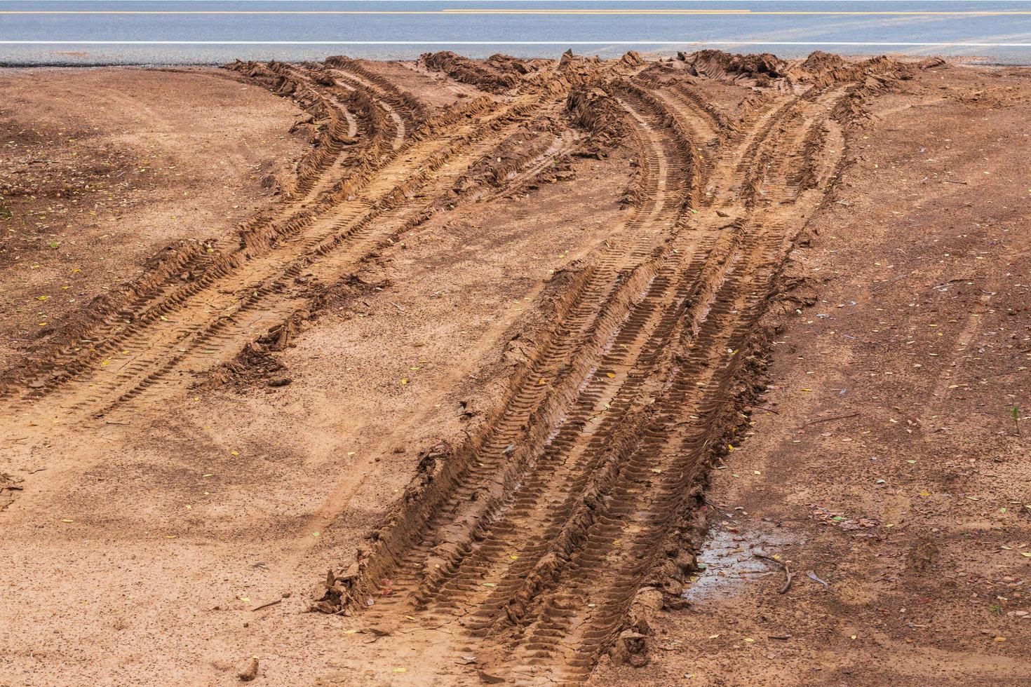 superficie fangosa, terreno sterrato con tracce di ruote su strade asfaltate. foto