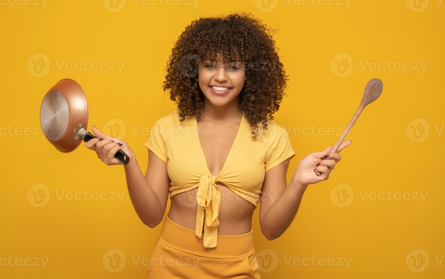 utensili da cucina. donna di cucina in cucina con padella e cucchiaio di legno. casalinga che balla. foto