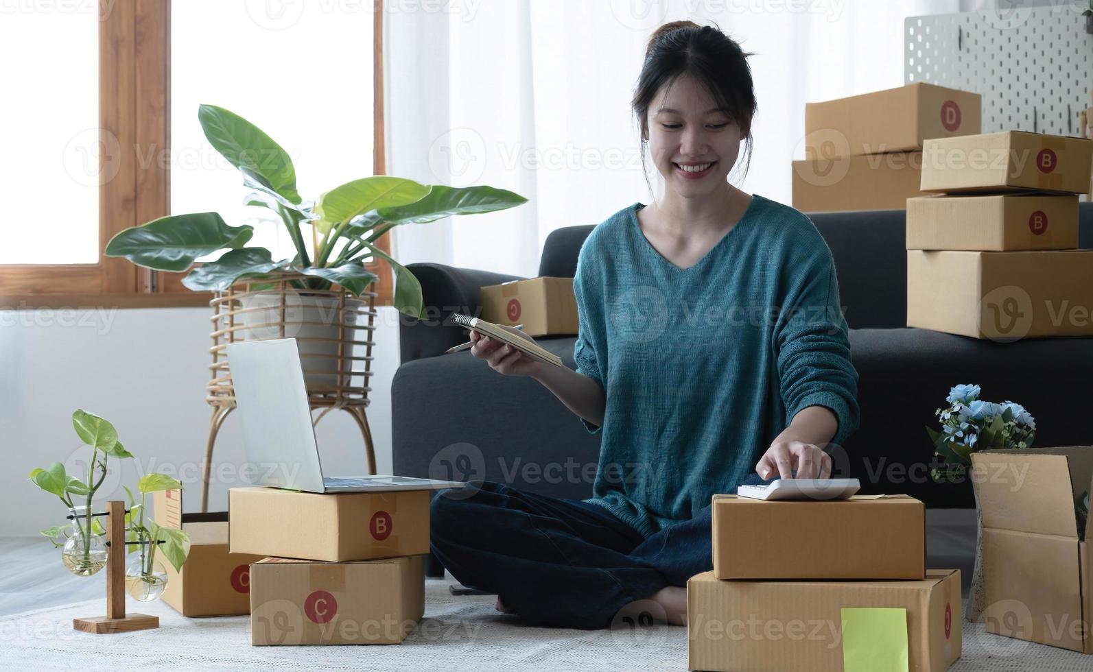 le donne asiatiche scrivono una nota di ordini di merci con una faccia sorridente nel concetto di PMI, attività di e-commerce foto