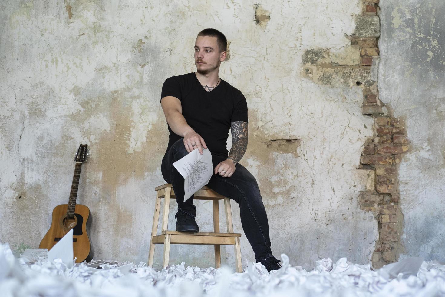 giovane maschio con la chitarra nella stanza vuota, musicista e cantautore da solo in studio foto