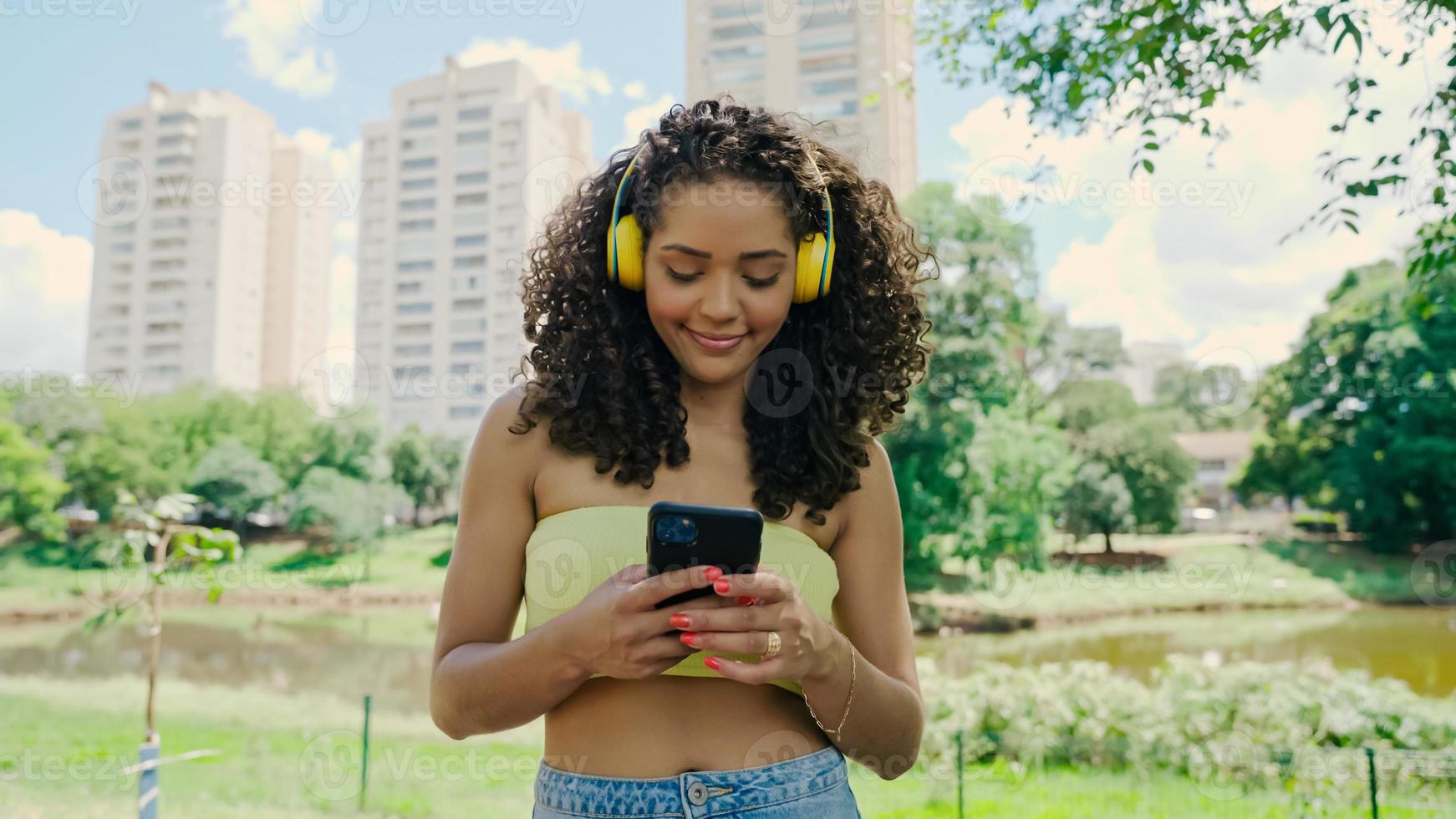 donna latina che utilizza smartphone nel parco. ragazza brasiliana. foto