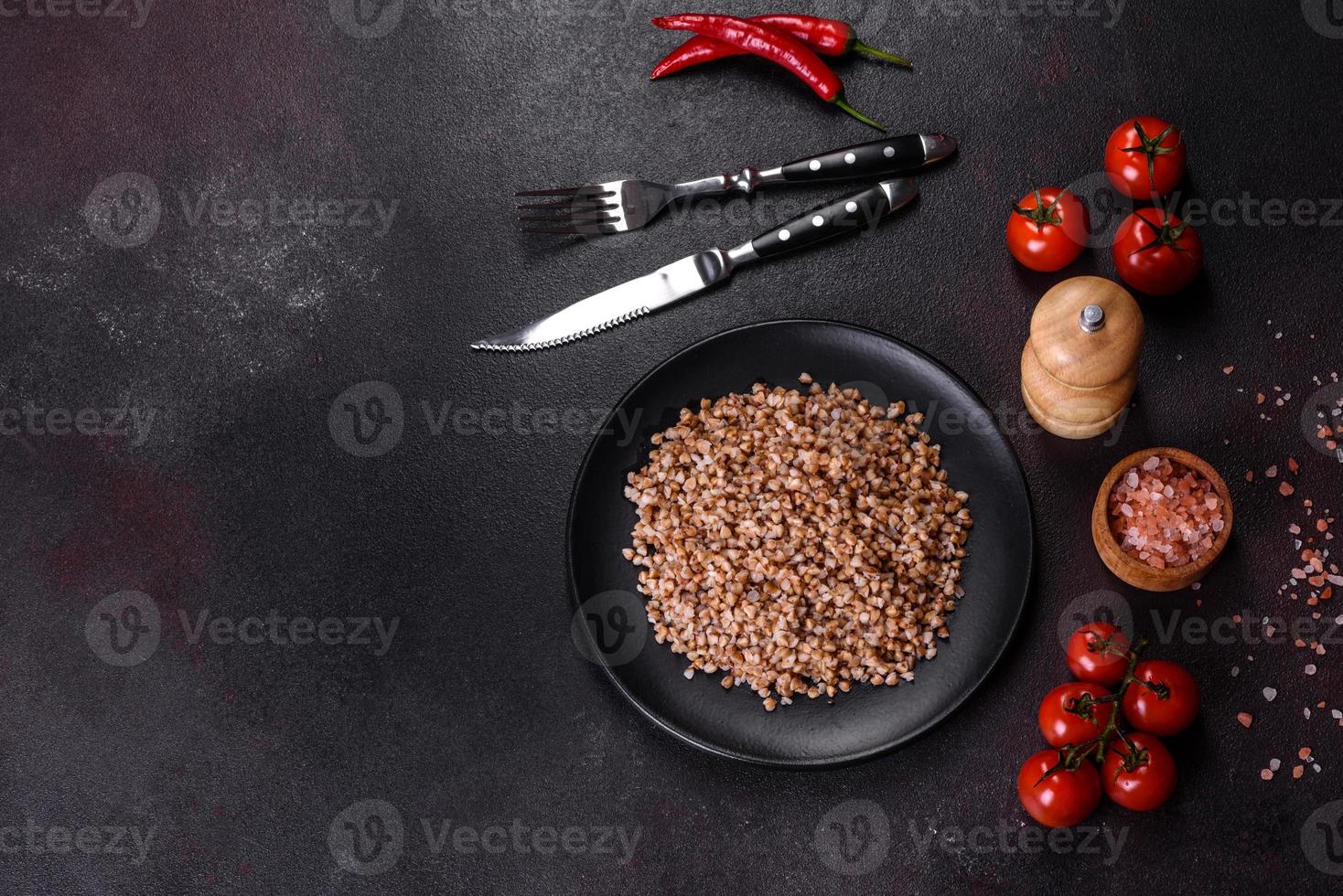 delizioso porridge di grano saraceno bollito fresco con verdure e spezie su un piatto nero foto
