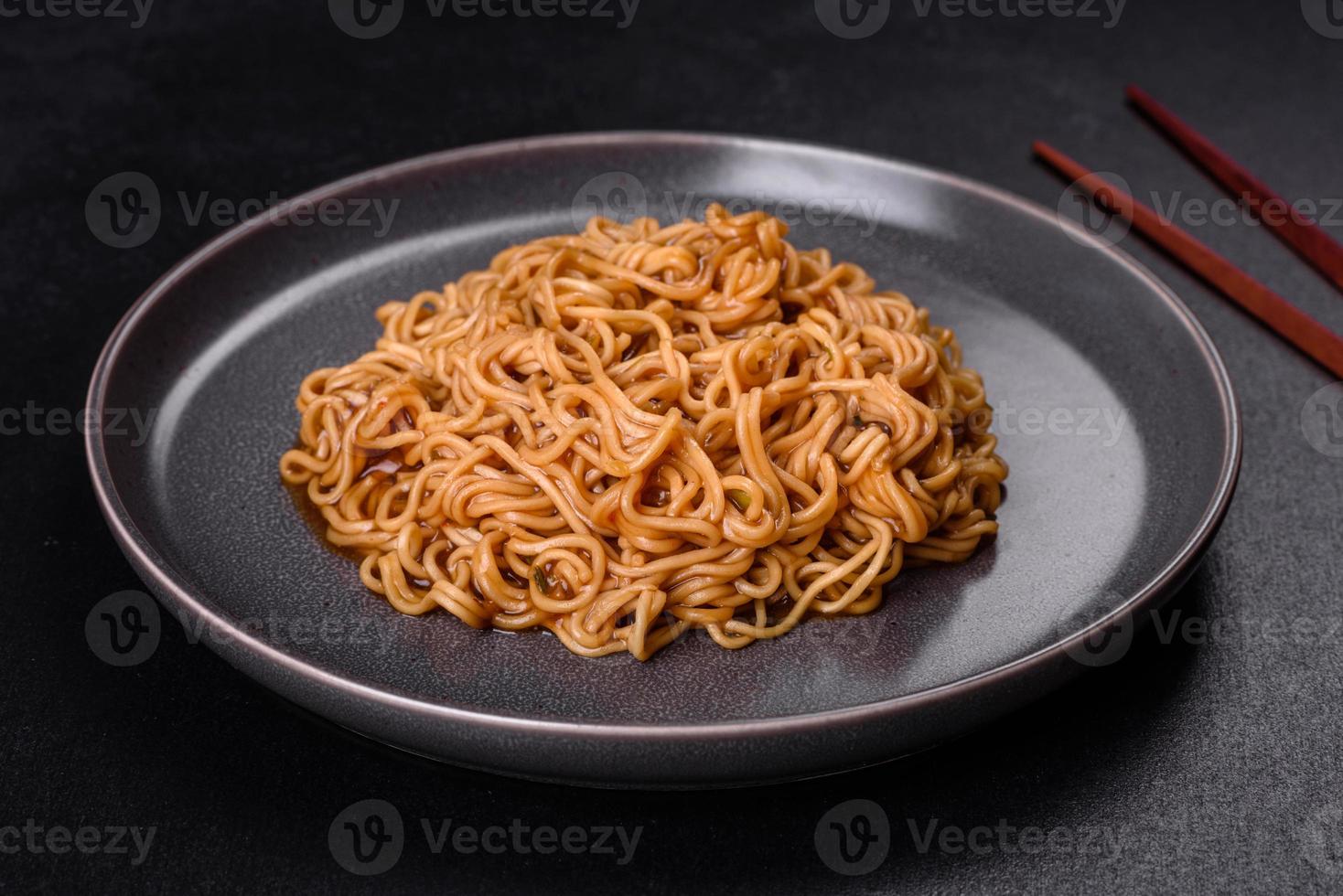 tagliatelle di farina di grano saraceno con salsa, sesamo, erbe e spezie su fondo di cemento scuro foto