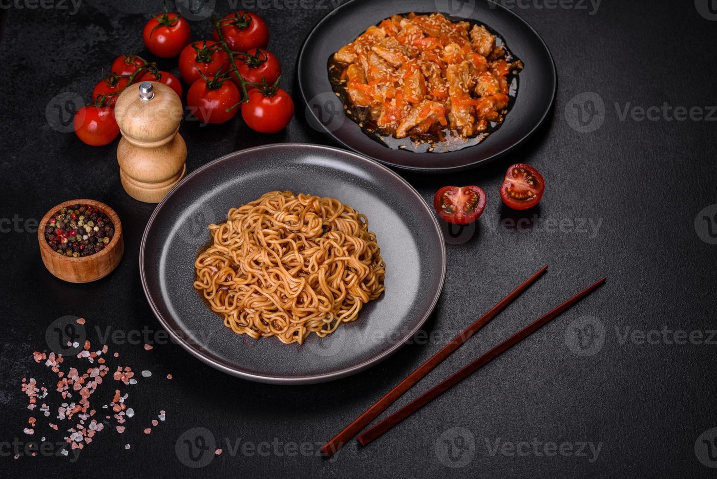 noodle tailandese e piatto di pollo su uno sfondo di cemento nero con bacchette cinesi e spazio per la copia foto