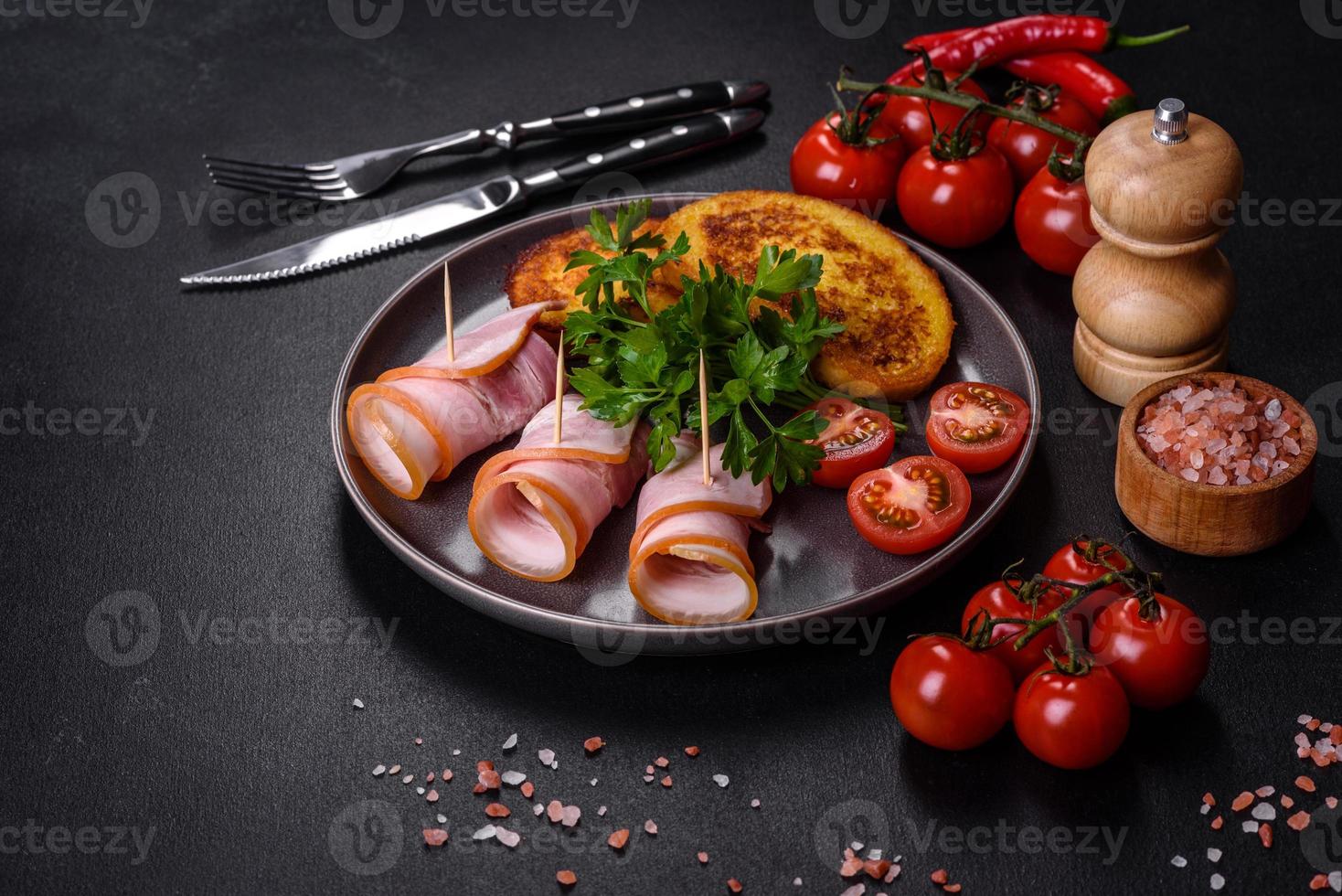 fette di deliziosa pancetta cruda o salata con spezie, sale, verdure ed erbe aromatiche su un tagliere di legno foto