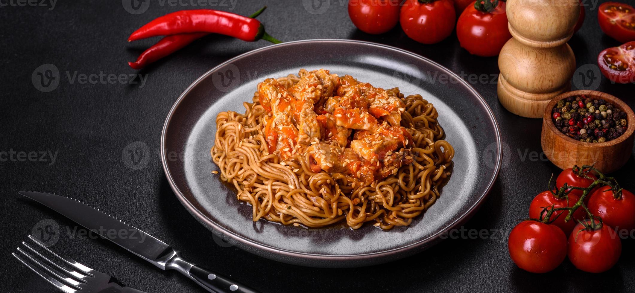 noodle tailandese e piatto di pollo su uno sfondo di cemento nero con bacchette cinesi e spazio per la copia foto