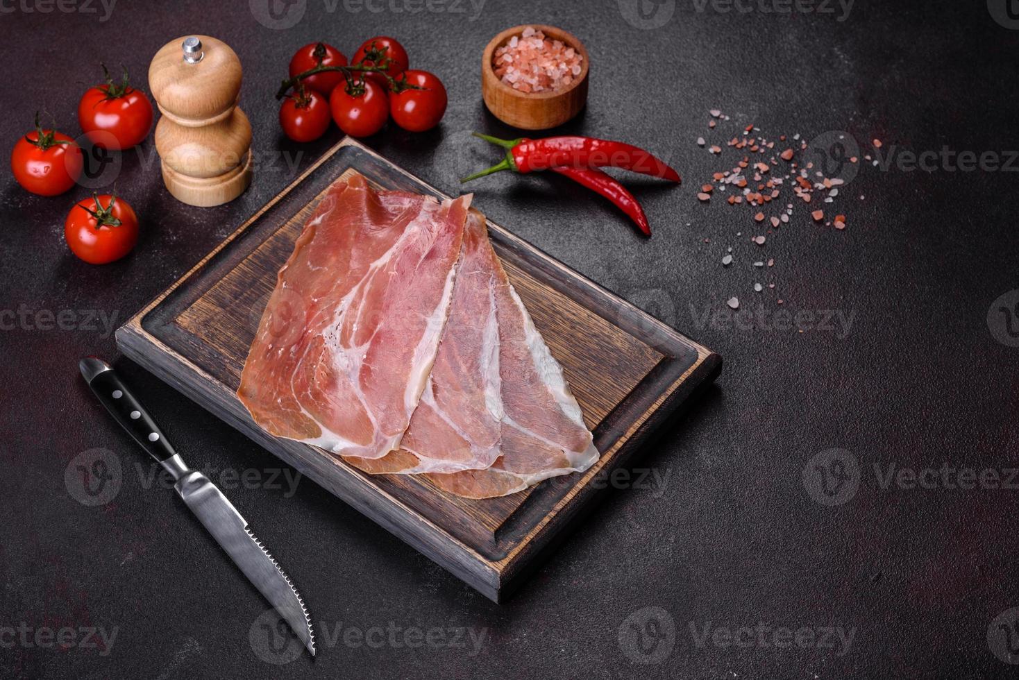 prosciutto crudo italiano o jamon spagnolo su un tagliere scuro foto