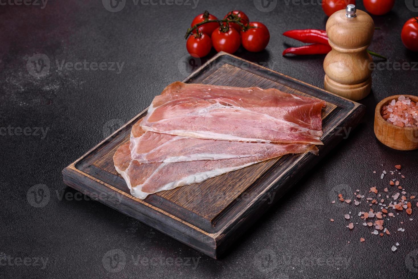 prosciutto crudo italiano o jamon spagnolo su un tagliere scuro foto