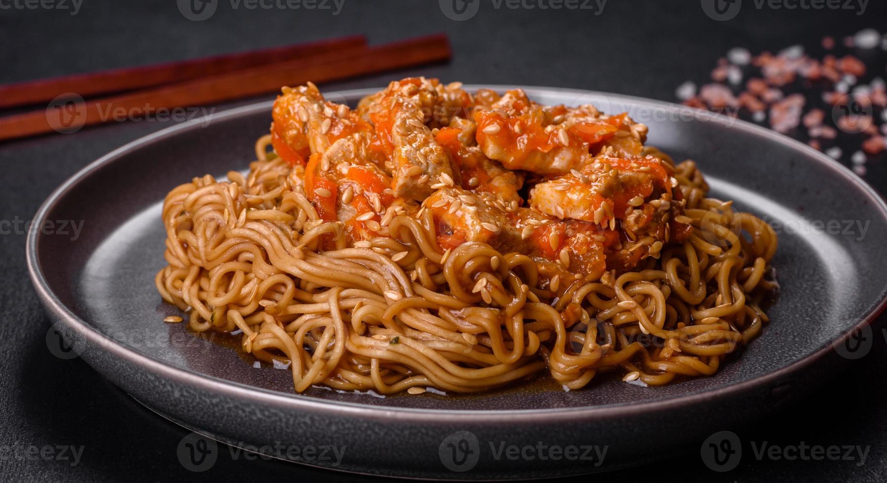 noodle tailandese e piatto di pollo su uno sfondo di cemento nero con bacchette cinesi e spazio per la copia foto