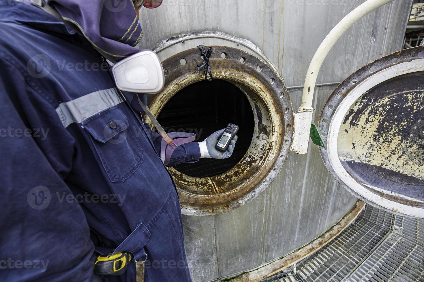 mano del lavoratore che tiene il rilevatore di gas ispezione test di sicurezza del gas al serbatoio inossidabile del passo d'uomo anteriore foto