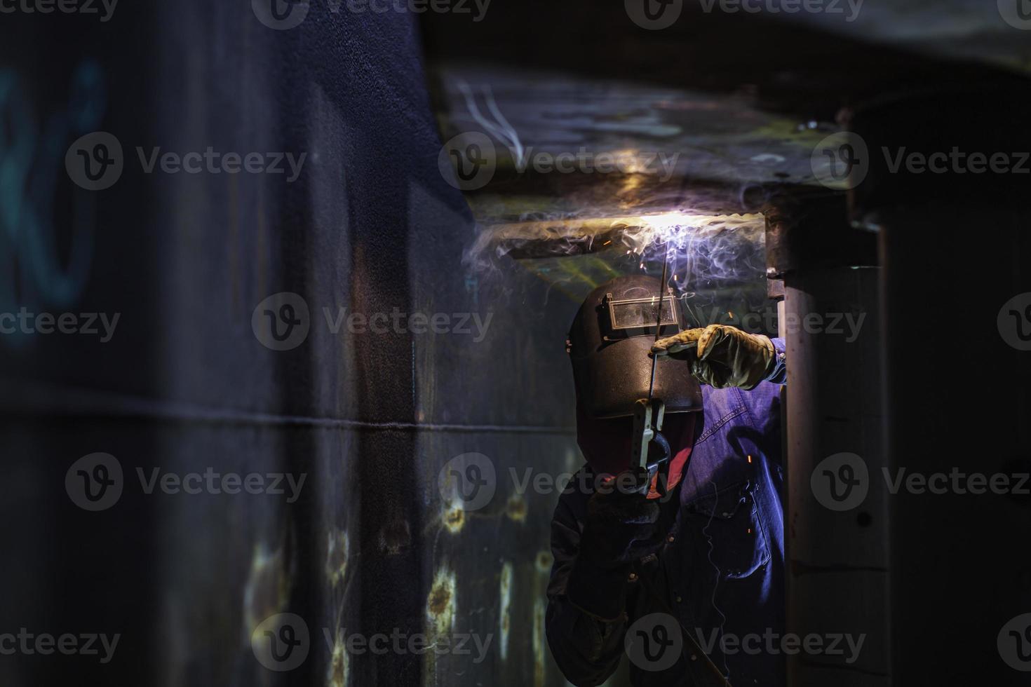 saldatura maschio lavoratore arco metallico è parte in macchinari serbatoio ugello conduttura costruzione serbatoio olio all'interno di spazi ristretti. foto