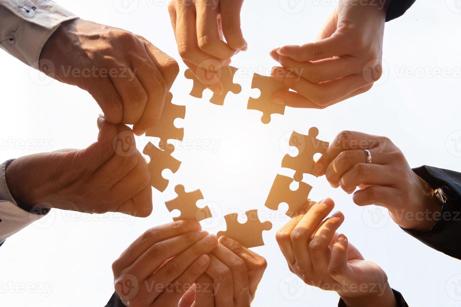 la mano di un uomo d'affari che tiene un puzzle di carta e risolve insieme il puzzle. il team aziendale assembla un puzzle. un gruppo di imprese che desidera riunire i pezzi del puzzle foto