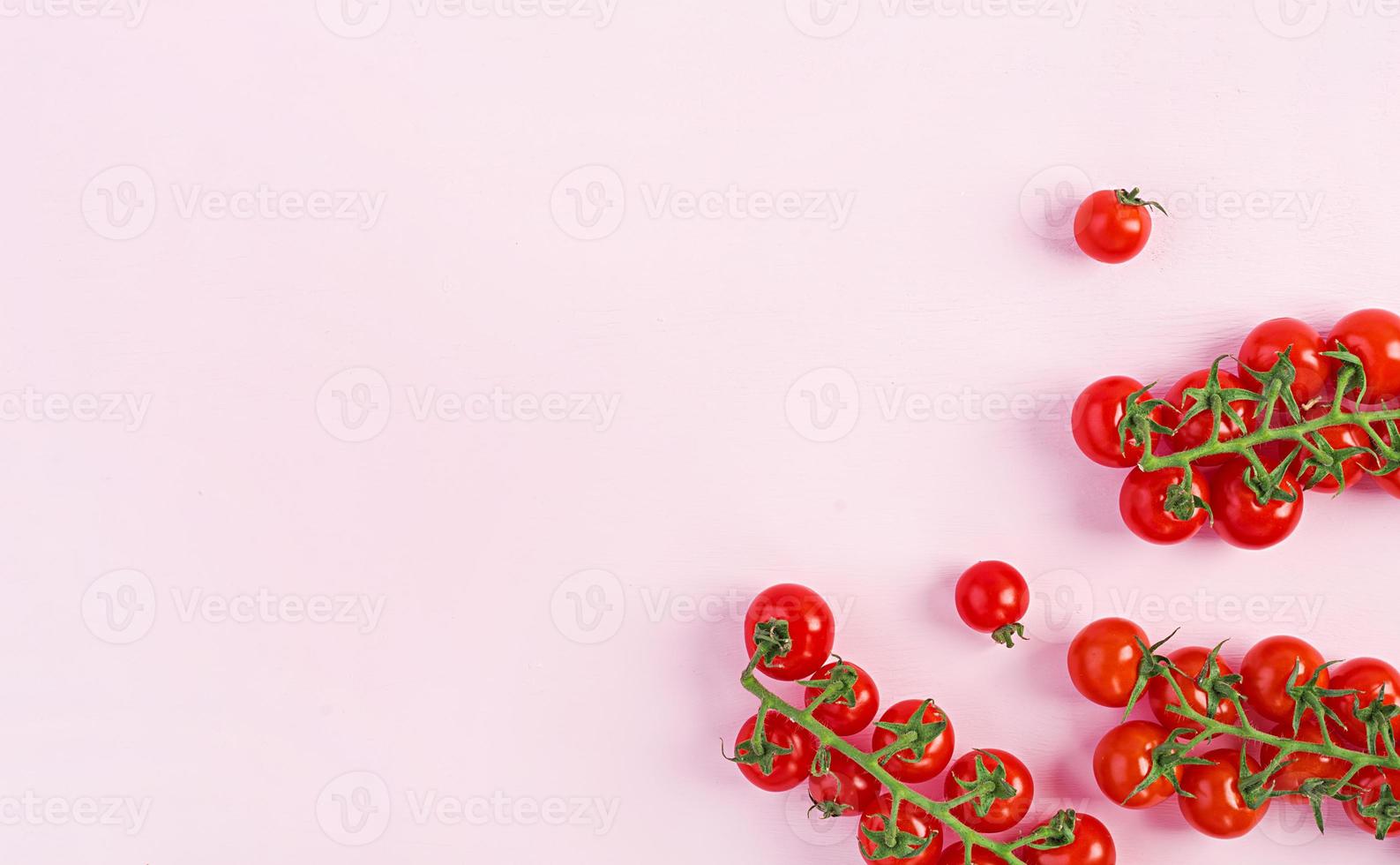 pomodorini rossi freschi isolati su sfondo rosa. vista dall'alto. disteso foto