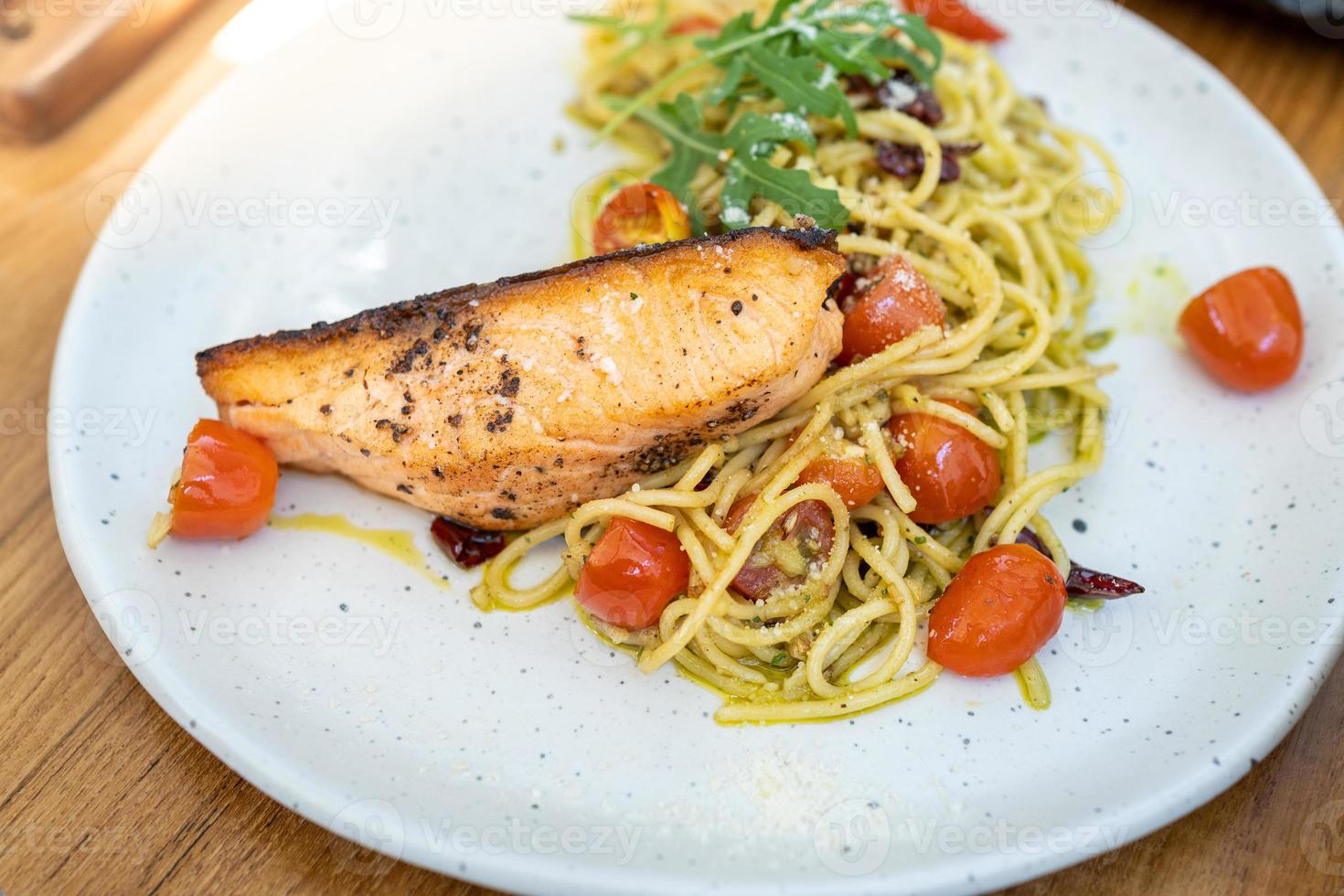 pasta spaghetti al pesto verde con filetto di salmone alla griglia - stile alimentare italiano foto