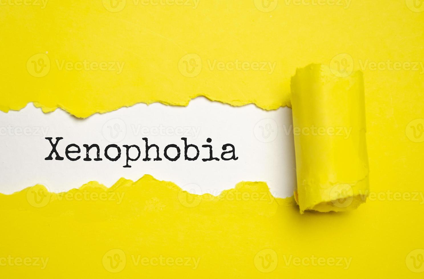 il testo xenofobia che appare dietro la carta marrone strappata foto