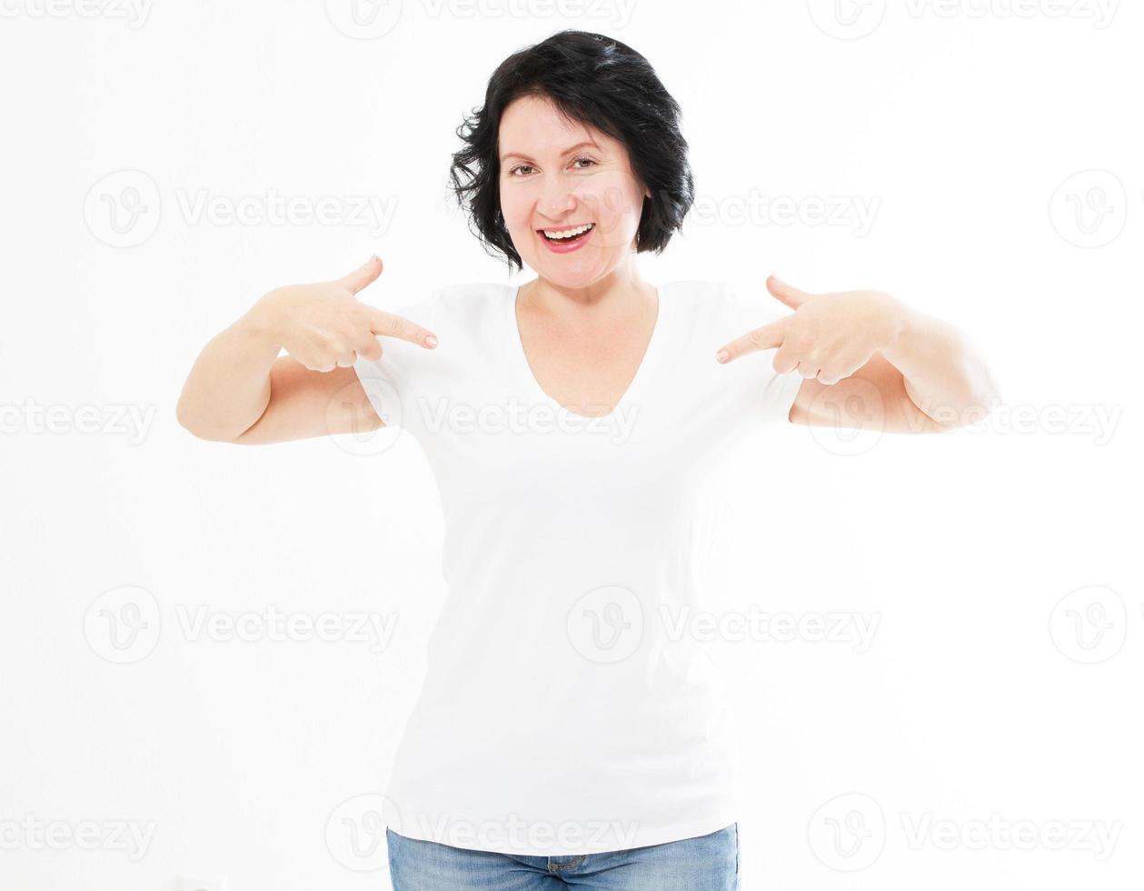 Ritratto di donna caucasica sorridente di mezza età che indossa una maglietta che punta a se stesso con il dito isolato su modello bianco e sfondo bianco. foto